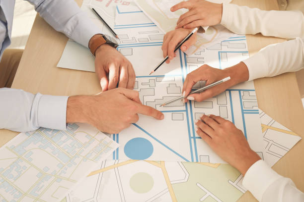 istock Professional cartographers working with cadastral map at table, closeup 1406680919