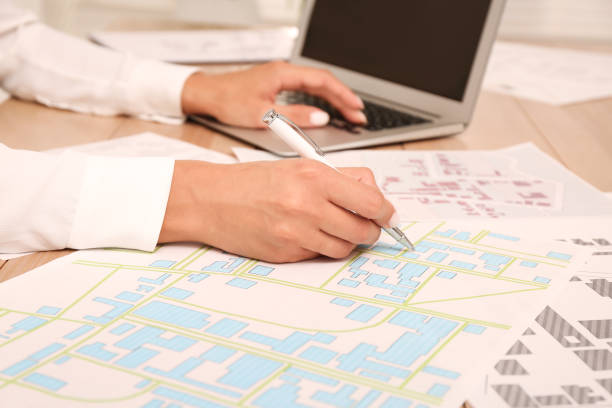 istock Professional cartographer working with cadastral map at wooden table, closeup 1406680920