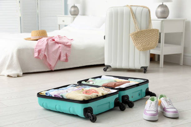 istock Open suitcase packed for trip and shoes on floor in room 1406680939