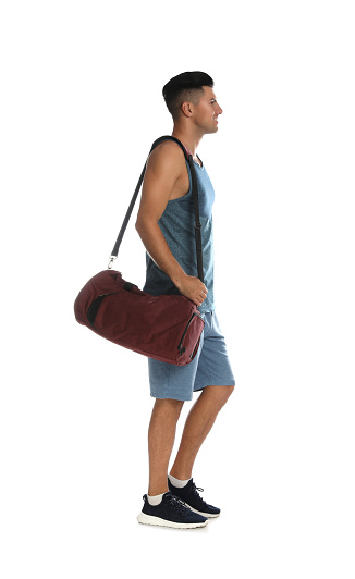 Handsome man with sports bag on white background