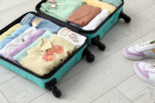 istock Open suitcase packed for trip and shoes on floor 1406682008