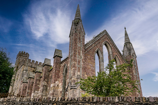 Front and perspective view of ruins of an old Gothic church in the Irish town of Wexford with blue sky and white clouds.