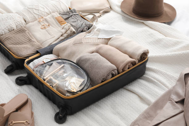 ベッドの上に折り畳まれた服、靴、アクセサリーが付いたオープンスーツケース - luggage ストックフォトと画像