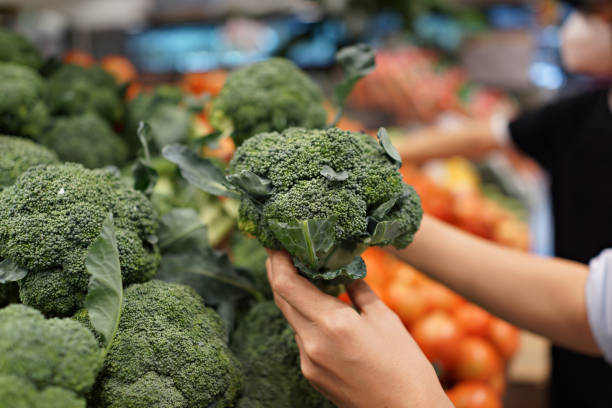 Customer Choosing Broccoli at Grocery Store Close Up stock photo