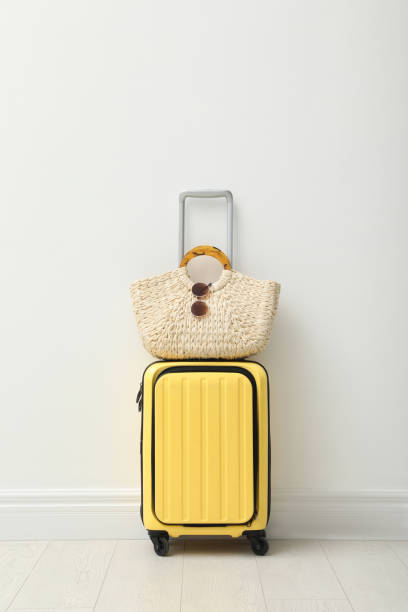 istock Suitcase packed for trip and summer accessories near white wall indoors 1406682603