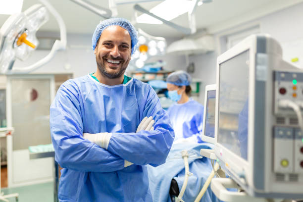 anestesista que trabaja en quirófano con monitores de control de protecive gear mientras seda al paciente antes del procedimiento quirúrgico en el hospital - anestesista fotografías e imágenes de stock