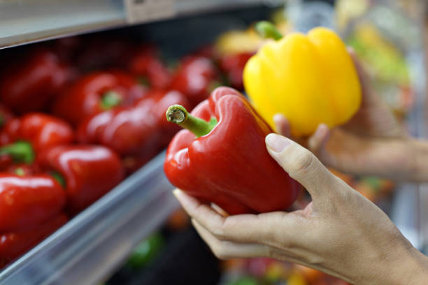 istock Customer Choosing Capsicums at Grocery Store Close Up 1406683413