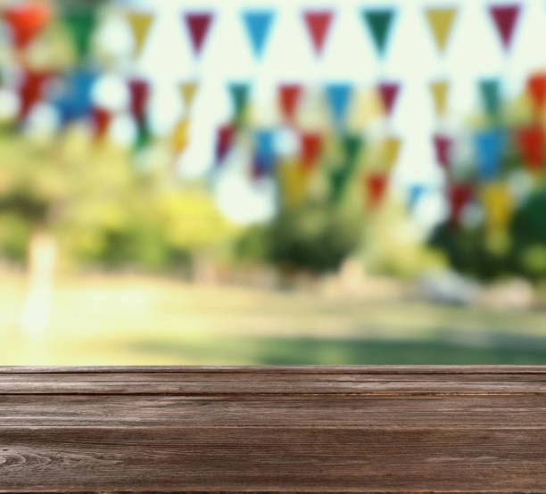 istock Empty wooden table in park decorated with bunting flags, space for design. Outdoor party 1406685659