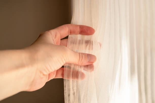 istock Woman adjusts ivory colored tulle with her hand, window light, close-up hands 1406686483