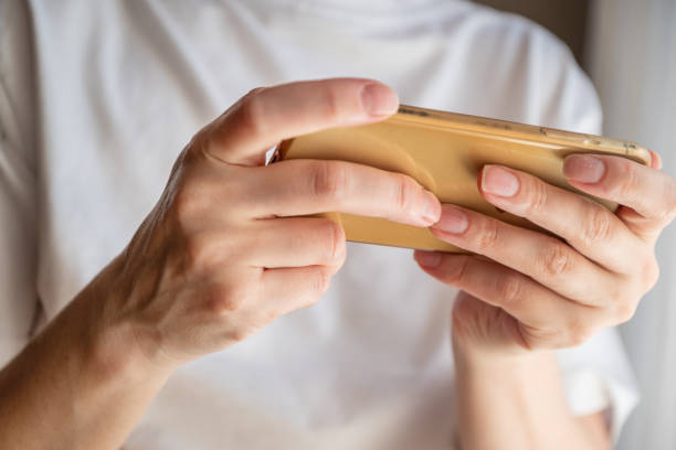 istock Woman holding mobile phone in her hands texting or playing games 1406686484