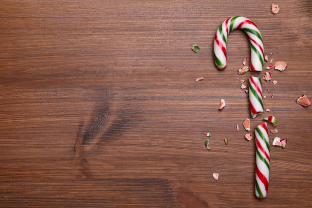 istock Broken sweet Christmas candy cane on wooden table, top view. Space for text 1406686853