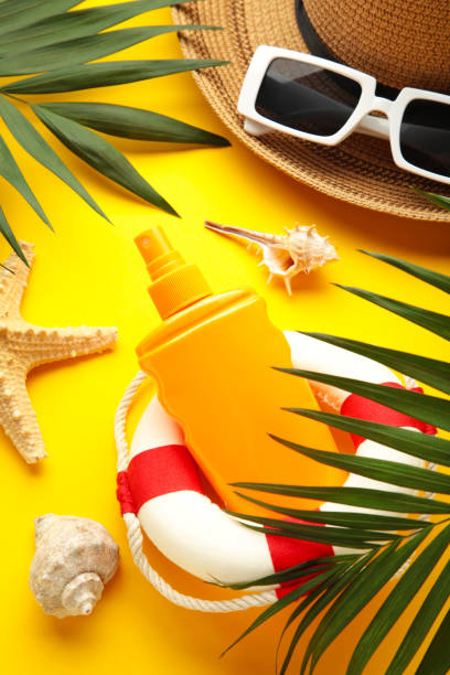 istock Beach flat lay accessories. Sun hat, palm branch, sunscreen bottle and seashells on yellow background. Summer travel holiday concept 1406687717