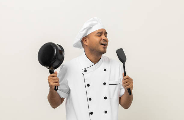 istock Super star singing masterchef. Young happy asian chef wearing uniform enjoy with singing voice and dancing in the kitchen on isolated white background. Indian man Occupation restaurant and hotel. 1406690800