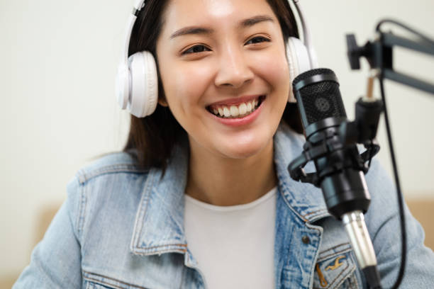 content creator woman host streaming her a podcast on laptop with headphones and microphone interview cheering guest conversation at broadcast studio. blogger motivation recording voice over radio. - voice over imagens e fotografias de stock