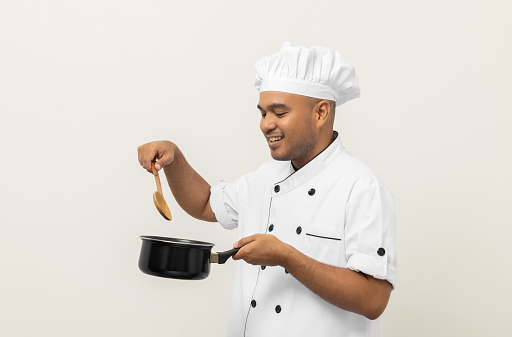 Young asian man chef in uniform holding soup pot utensils cooking in the kitchen various gesture action on isolated background. Indian man Occupation chef restaurant and hotel.
