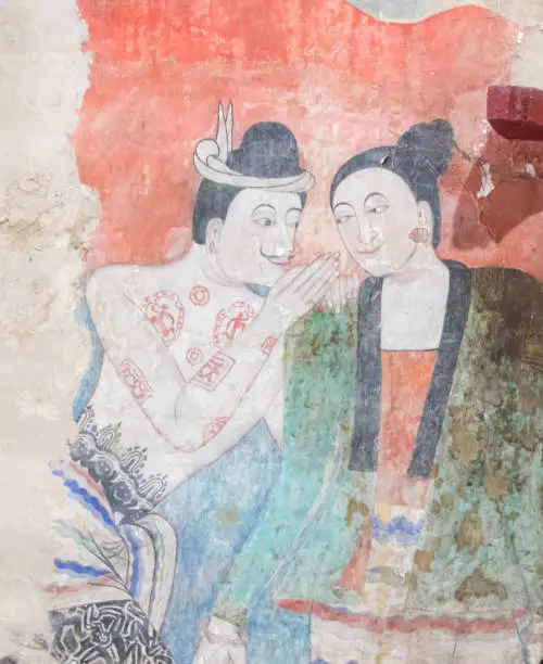 Photo of NAN, THAILAND  DECEMBER 26: Grandfather and Grandmother's curtain painting in Wat Phumin Which is a picture of whispering to love each other on DECEMBER 26 2020 in Nan, Thailand.