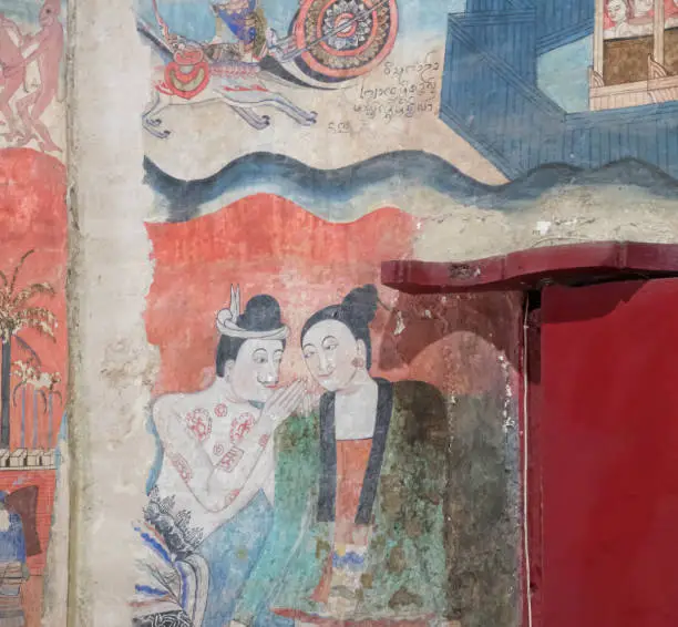 Photo of NAN, THAILAND  DECEMBER 26: Grandfather and Grandmother's curtain painting in Wat Phumin Which is a picture of whispering to love each other on DECEMBER 26 2020 in Nan, Thailand.