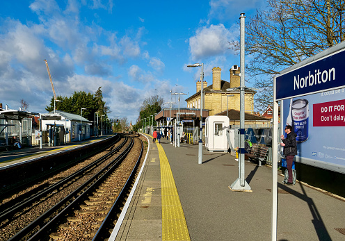 London, UK- February 17, 2022: People waiting for the train on the platform of Norbiton station. Norbiton Railway Station is a railway station located in Norbiton, a suburb in the Royal Borough of Kingston upon Thames, in southwest London.