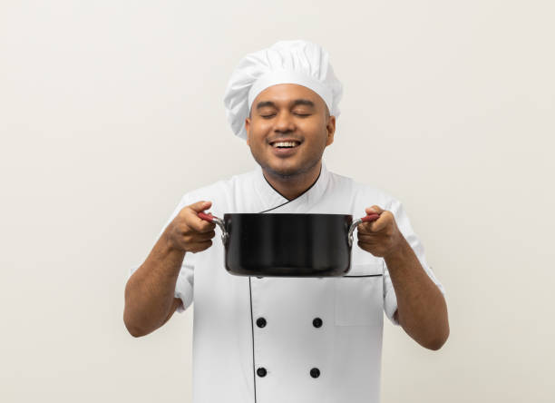 istock Smiling Young man chef in uniform gesture smelling empty hot pot stew soup delicious dish menu good taste on isolated. Cooking man Occupation chef People in kitchen restaurant and hotel. 1406692456