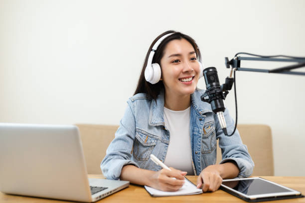 content creator woman host streaming her a podcast on laptop with headphones and microphone interview cheering guest conversation at broadcast studio. blogger motivation recording voice over radio. - voice over imagens e fotografias de stock