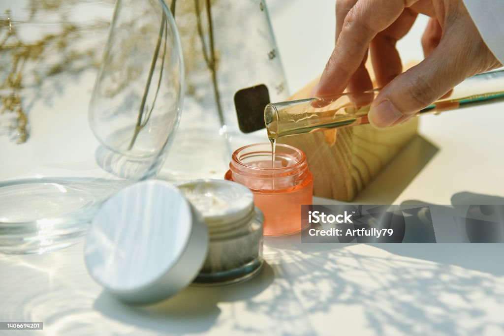 Scientist mixing natural skin care beauty products, Organic botany extraction and scientific laboratory glassware, Blank label cosmetic container for branding mock-up. Mixing Stock Photo