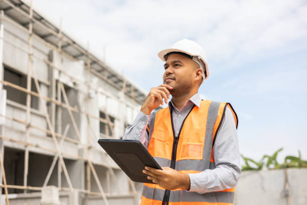 istock Confident asian engineer man Using tablet for checking and maintenance to inspection at modern home building construction. Architect working with white safety helmet in construction site 1406694260