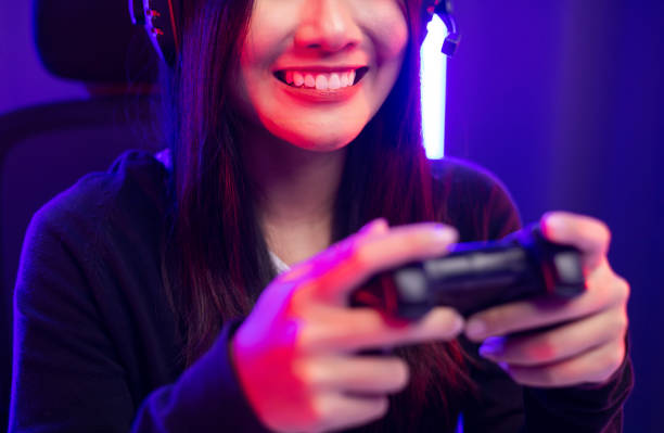 istock Close up hands Playing video game. Young pretty woman holding joystick controller console. Female Professional Streaming playing game online in dark room neon light. 1406694355