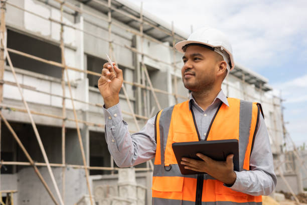 istock Confident asian engineer man Using tablet for checking and maintenance to inspection at modern home building construction. Architect working with white safety helmet in construction site 1406694571