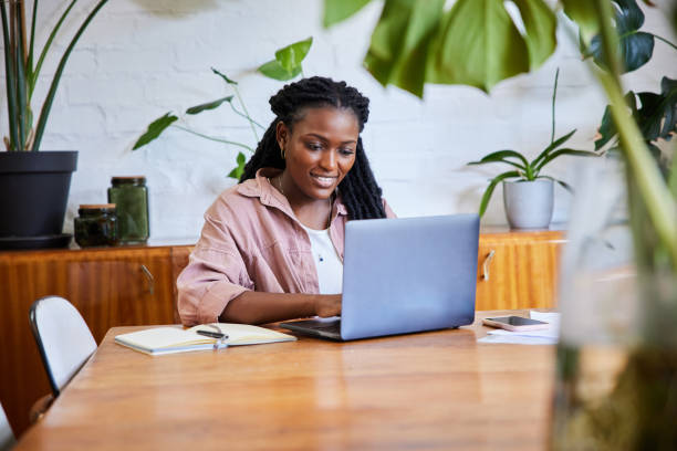 istock Smiling young woman working remotely from home on a laptop 1406697848