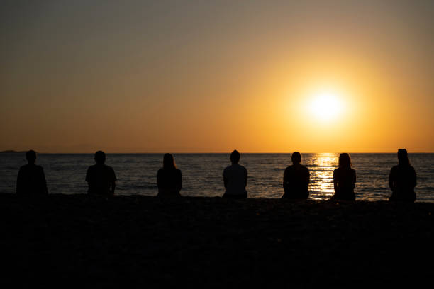 istock group of people practicing yoga on the beach at sunrise 1406697869