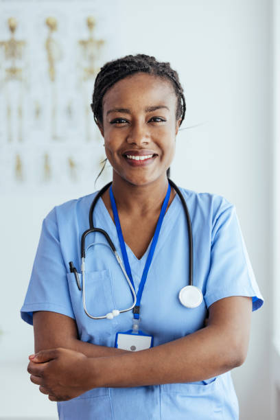 Young female nurse with folded arms standing in hospital stock photo