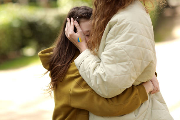 primer plano de una joven madre cariñosa que abraza a su triste hija pequeña con la bandera a mano al aire libre. paz, no guerra, ayuda, detenga la agresión rusa. invasión de rusia en ucrania. foto de alta calidad - worship place fotografías e imágenes de stock