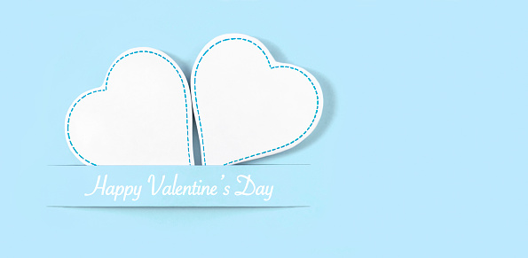 White heart shaped ornaments on pastel blue background with copy space and Valentine’s Day message