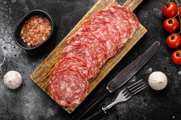 Thinly Sliced Milano salami, on black dark stone table background, top view flat lay Thinly Sliced Milano salami set, on black dark stone table background, top view flat lay turkish sausage stock pictures, royalty-free photos & images