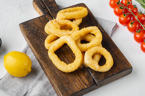 Fried squid rings breaded set, on serving board, on white stone table background