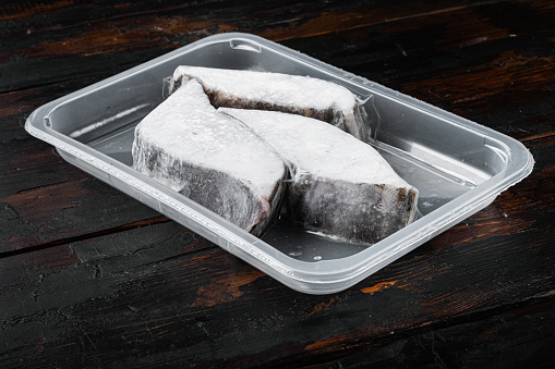 Halibut iced fillet plastic pack set, on old dark  wooden table background