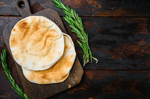 Pita flat bread, on old dark  wooden table background, top view flat lay, with copy space for text