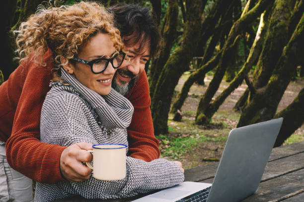 istock Happy Couple Using Laptop Outdoors 1406711911