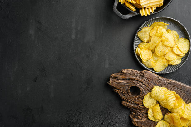 istock Sour Cream Onion Flavored Potato Chips on black dark stone table background, top view flat lay, with copy space for text 1406713657