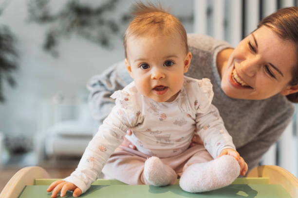 Smiling baby girl playing with her mom. Mom playing with her six month old daughter. Baby climbing over obstacles.