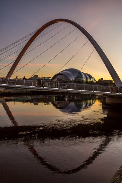 die millennium bridge in newcastle bei sonnenuntergang, die sich im fast stillen fluss tyne unter - millennium bridge stock-fotos und bilder