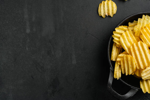 istock Ridged potato chips on black dark stone table background, top view flat lay, with copy space for text 1406714119