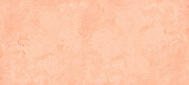 istock Pastel peach color painted old rough cement plaster widescreen texture. Aged exterior wall light orange wide background 1406715282