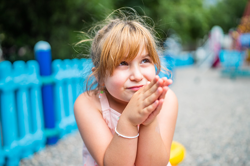 A portrait of a cute little girl in a public park.
