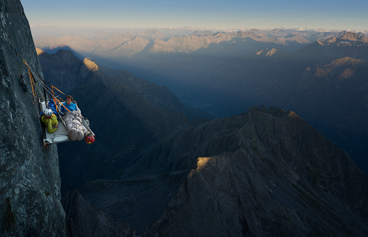 Climbers going to sleep on a portaledge very high above the ground on the mountain face