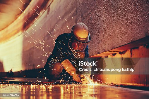 istock Male worker metal cutting spark on tank bottom steel plate with flash of cutting light close up wear protective gloves and mask 1406716242