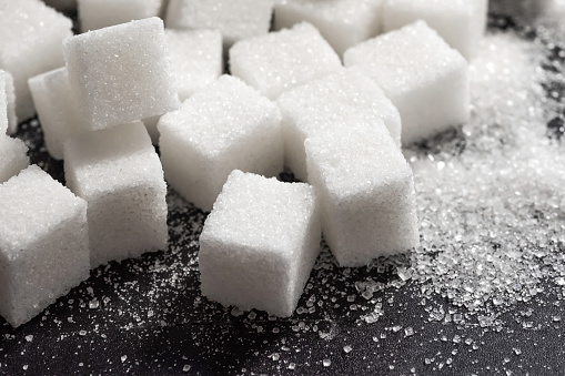 Cubes of refined sugar on a dark table close-up.