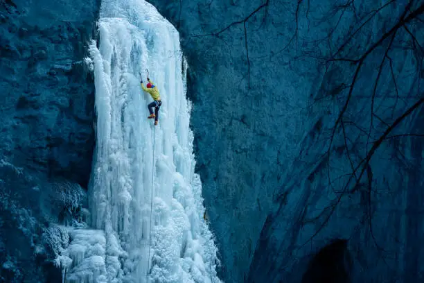 Strong ice climber climbing a frozen waterfall