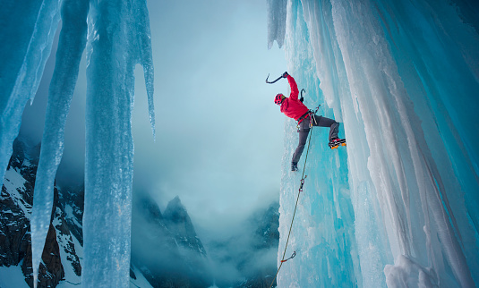 Climber ascending on a steep ice wall