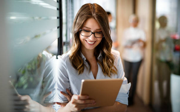 istock Attractive young businesswoman using a digital tablet while standing in front of windows in office 1406721397